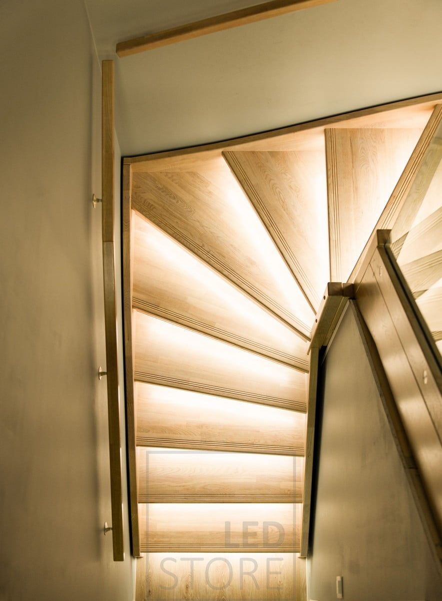 Wooden staircase illuminated by led strips on the steps